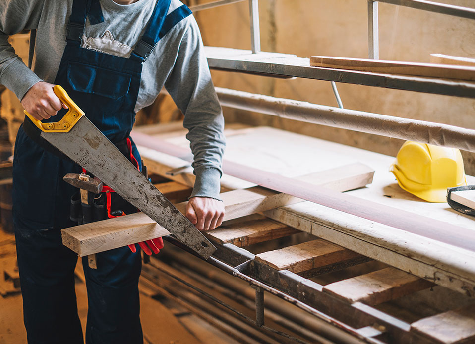 A man using a saw to cut plywood